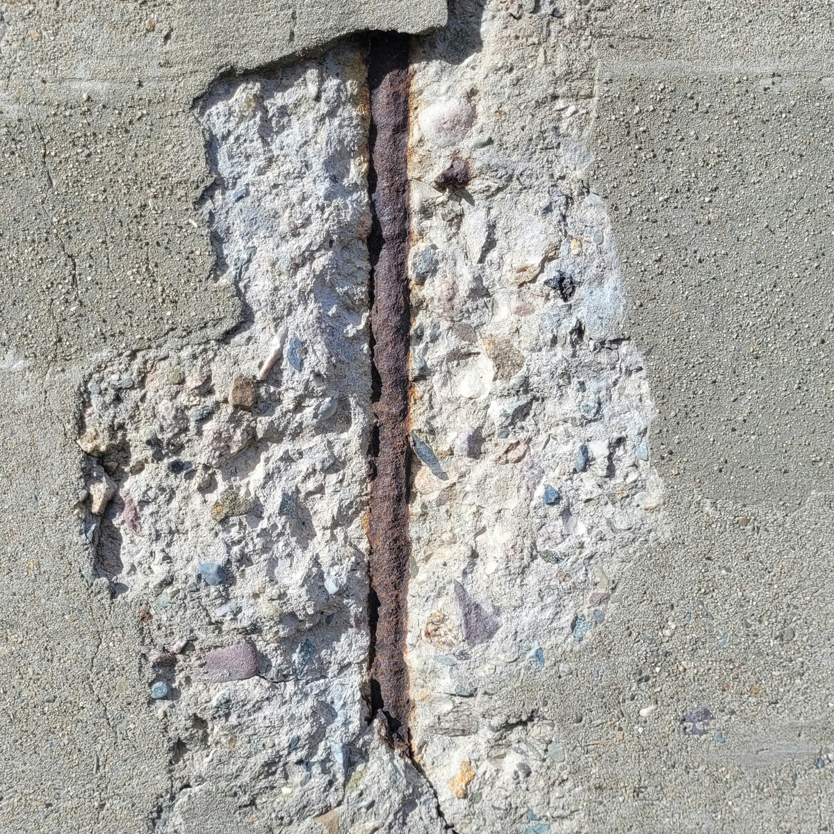 Close-up of cracked and deteriorated concrete exposing rusted reinforcement, showing foundation damage requiring repair in Pompano Beach, FL.