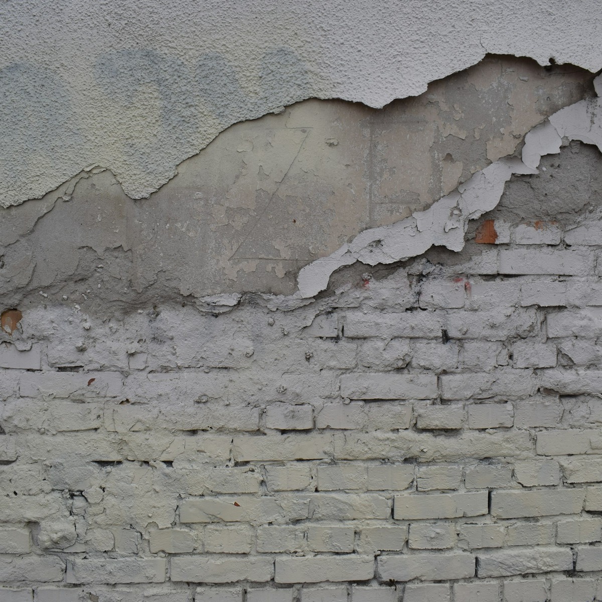 Close-up of cracked and deteriorating foundation masonry with peeling surface material, showing visible damage requiring foundation repair near me.